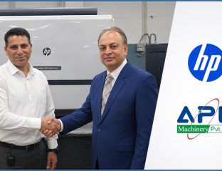 HP and APL Machinery representatives shaking hands beside an HP Indigo digital press